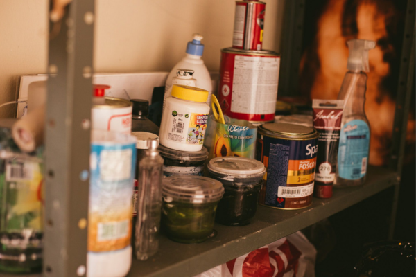Latas e frascos de diferentes produtos armazenados em uma prateleira.